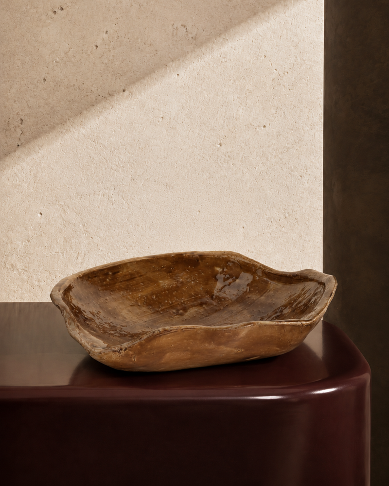 Organic-shaped stoneware bowl in brown glaze with wavy rim, styled on a tabletop