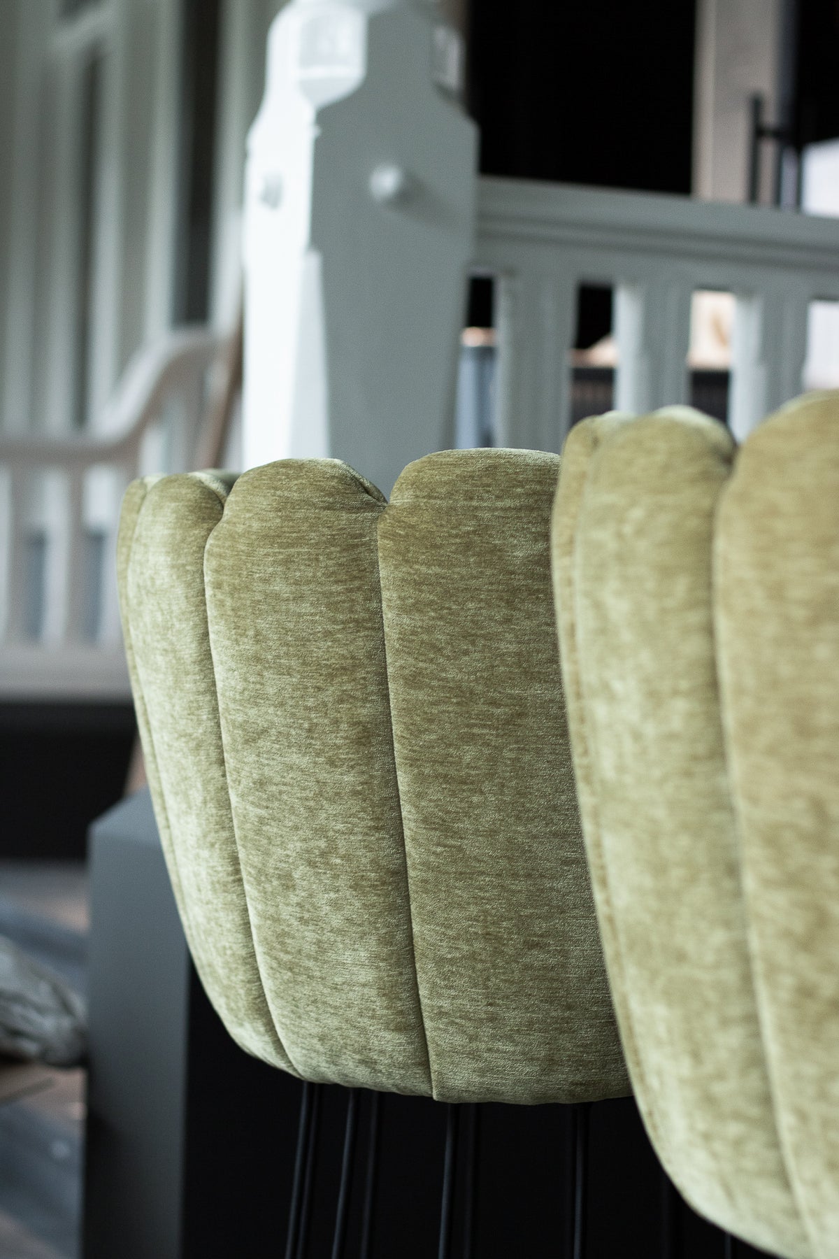 Westervilla restaurant styled by Berries Agency: close-up of a scalloped sage-green velvet chair against a white classic banister