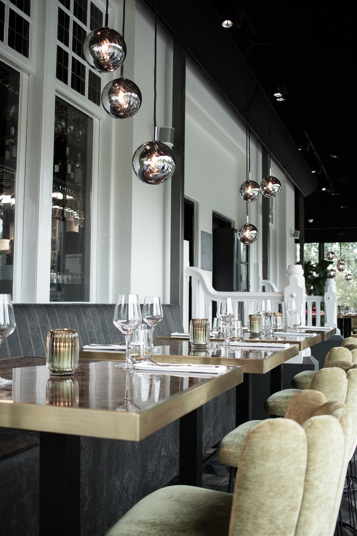 Westervilla restaurant styled by Berries Agency: long dining room with brass-edged tables, green velvet chairs and smoked glass pendants