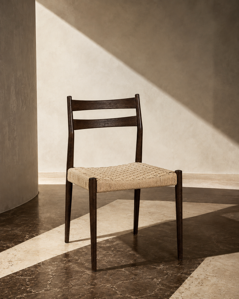 Dark oak dining chair without armrests and natural woven cord seat, styled in a sunlit interior