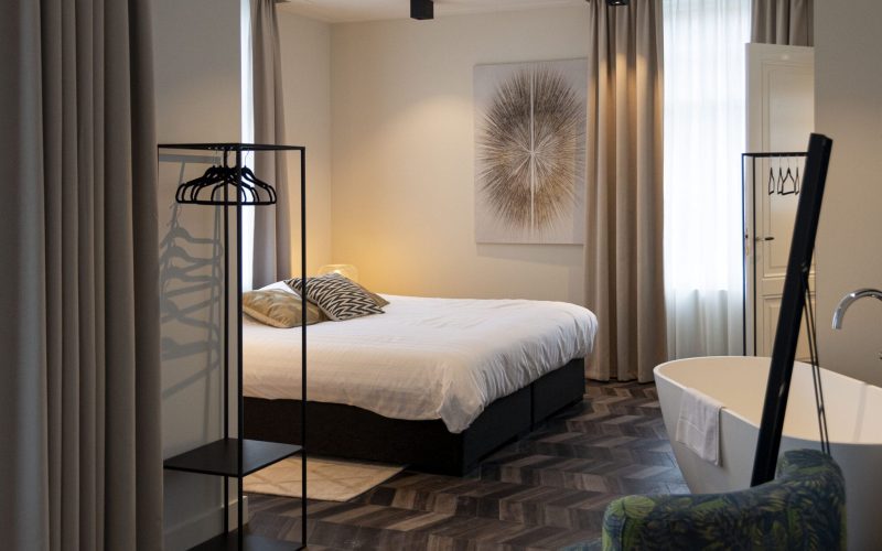 Westervilla superior suite styled by Berries Agency: bed, freestanding bathtub, open clothes rail and botanical velvet seating
